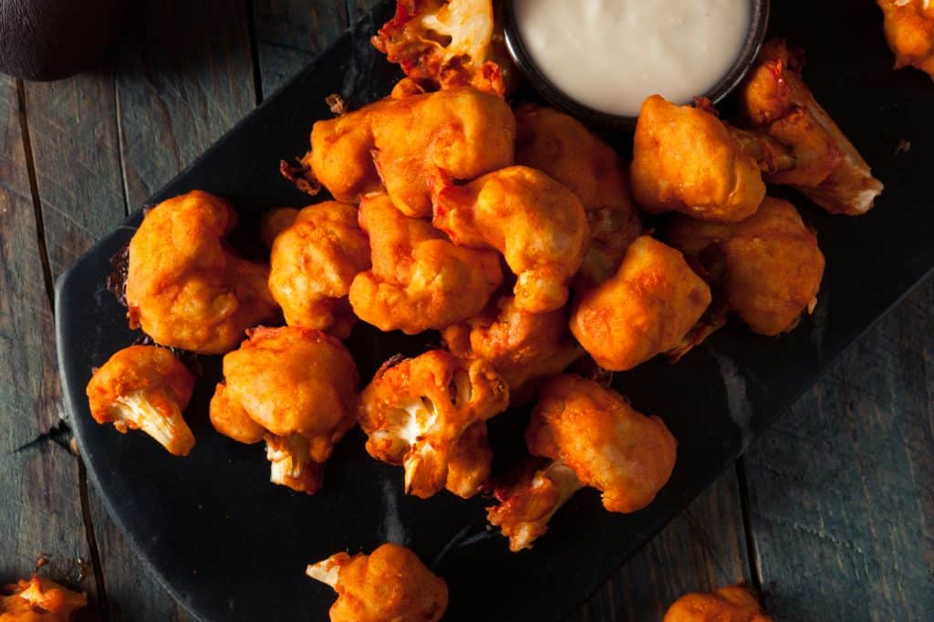 a dish of buffalo cauliflower bites with a creamy white dressing