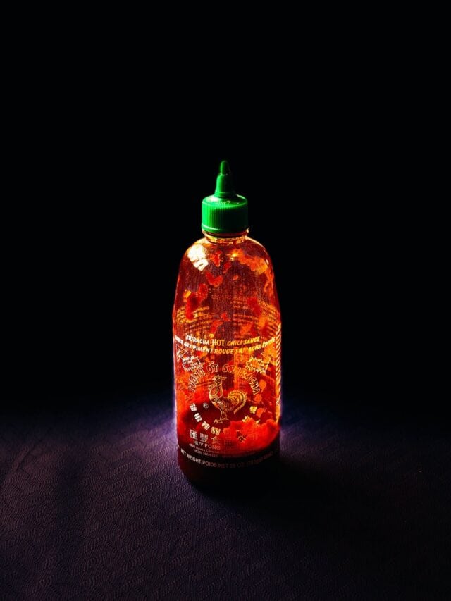 a bottle of huy fong sriracha in dramatic lighting