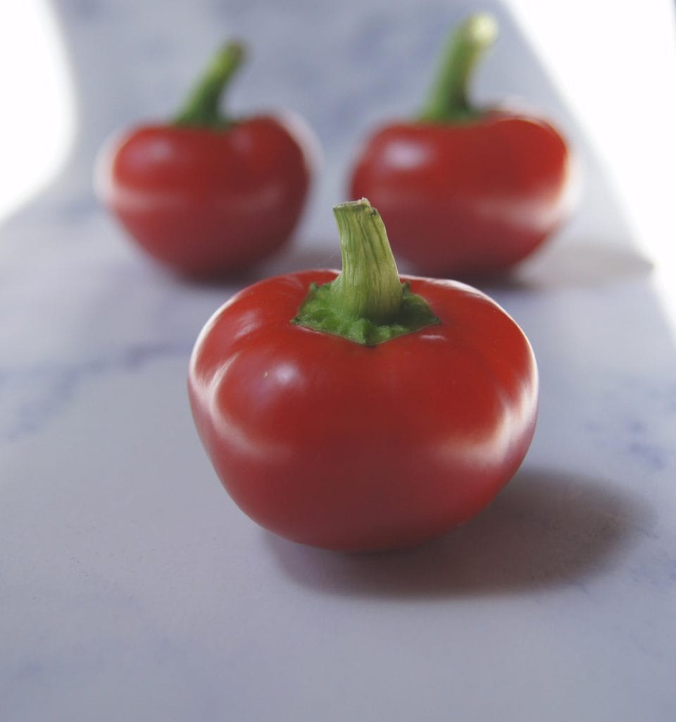 three cherry peppers on marble background.