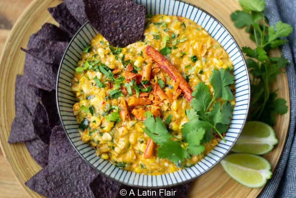 bowl of corn dip and blue chips.