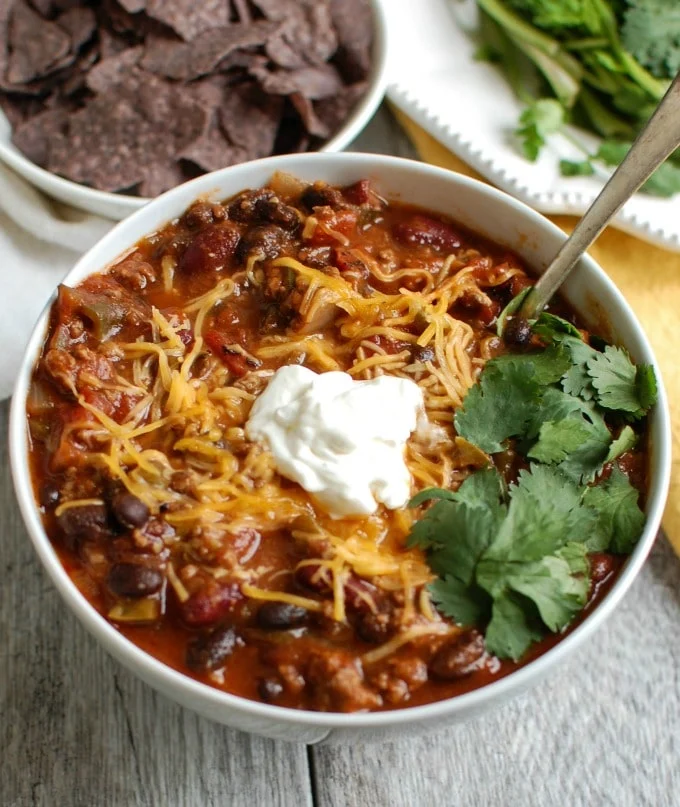 a bowl of chili garnished with cilantro and sour cream.