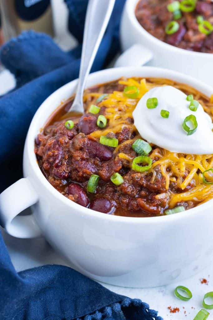 a bowl of chili topped with sour cream and green onions.