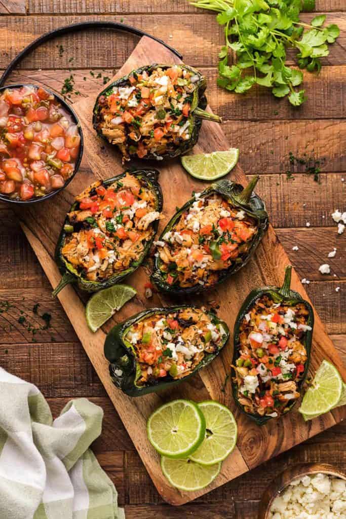 five stuffed pepper halves on a wooden board.