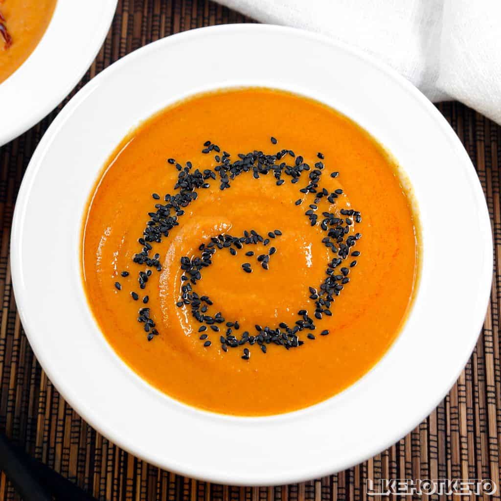 bowl of range soup with a spiral of black sesame seeds.