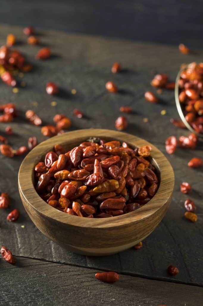 dried piquin peppers in a wood bowl.