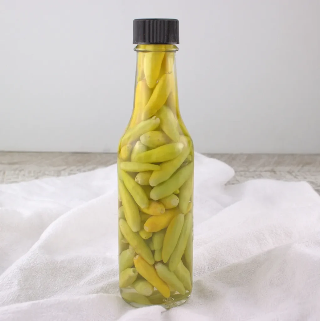 hot sauce bottle full of mini green-yellow peppers.