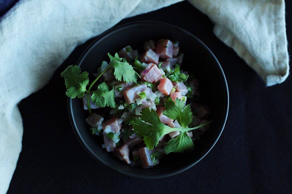 dim lighting bowl of tuna ceviche topped with cilantro.