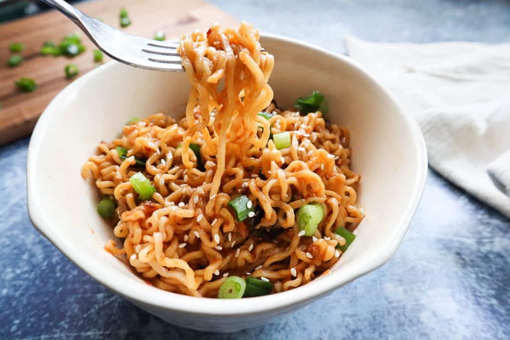 fork lifting ramen out of white bowl.