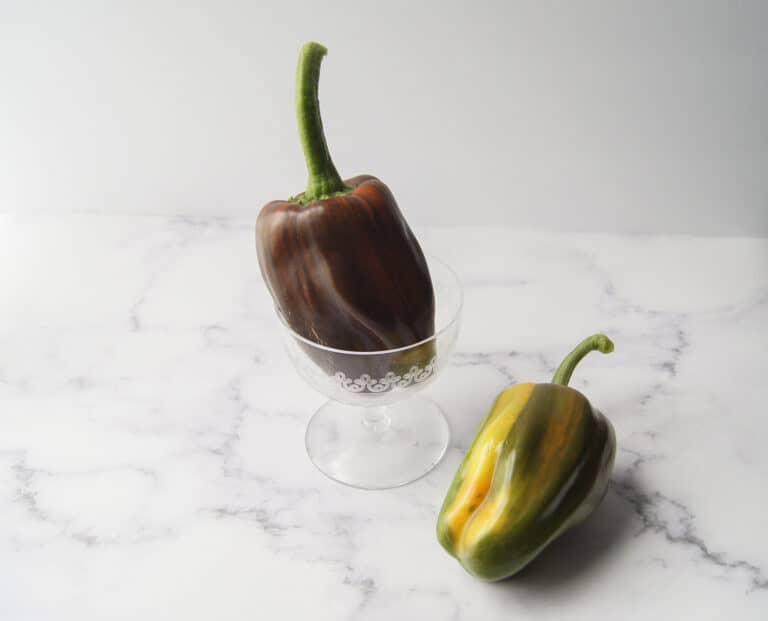 two candy cane bell peppers, one in a glass dish.