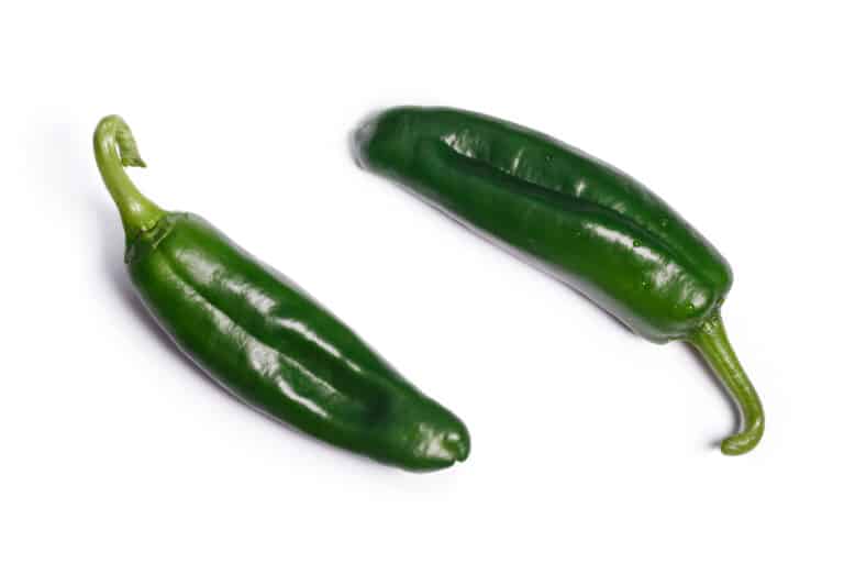 two green anaheim peppers on a white background